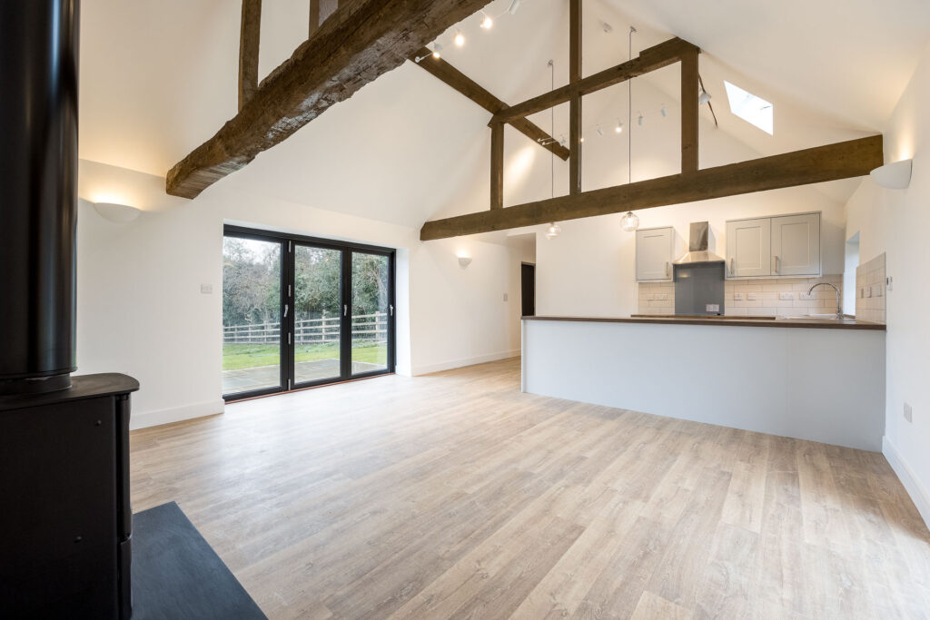 An internal view of a cosy living space with exposed wooden beams and a view onto the garden at Hard to Find Farm