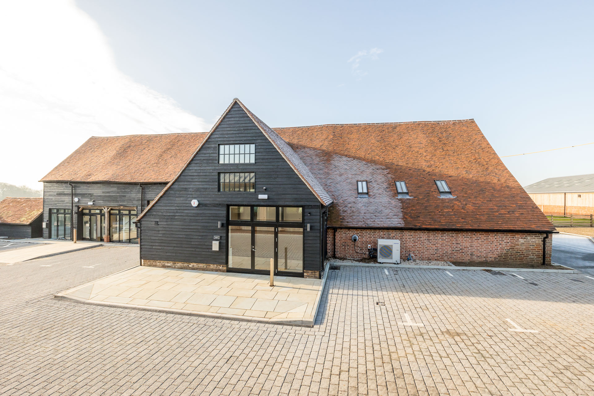 External view of the refurbished Barn D with paved parking in front at Hard to Find Farm.