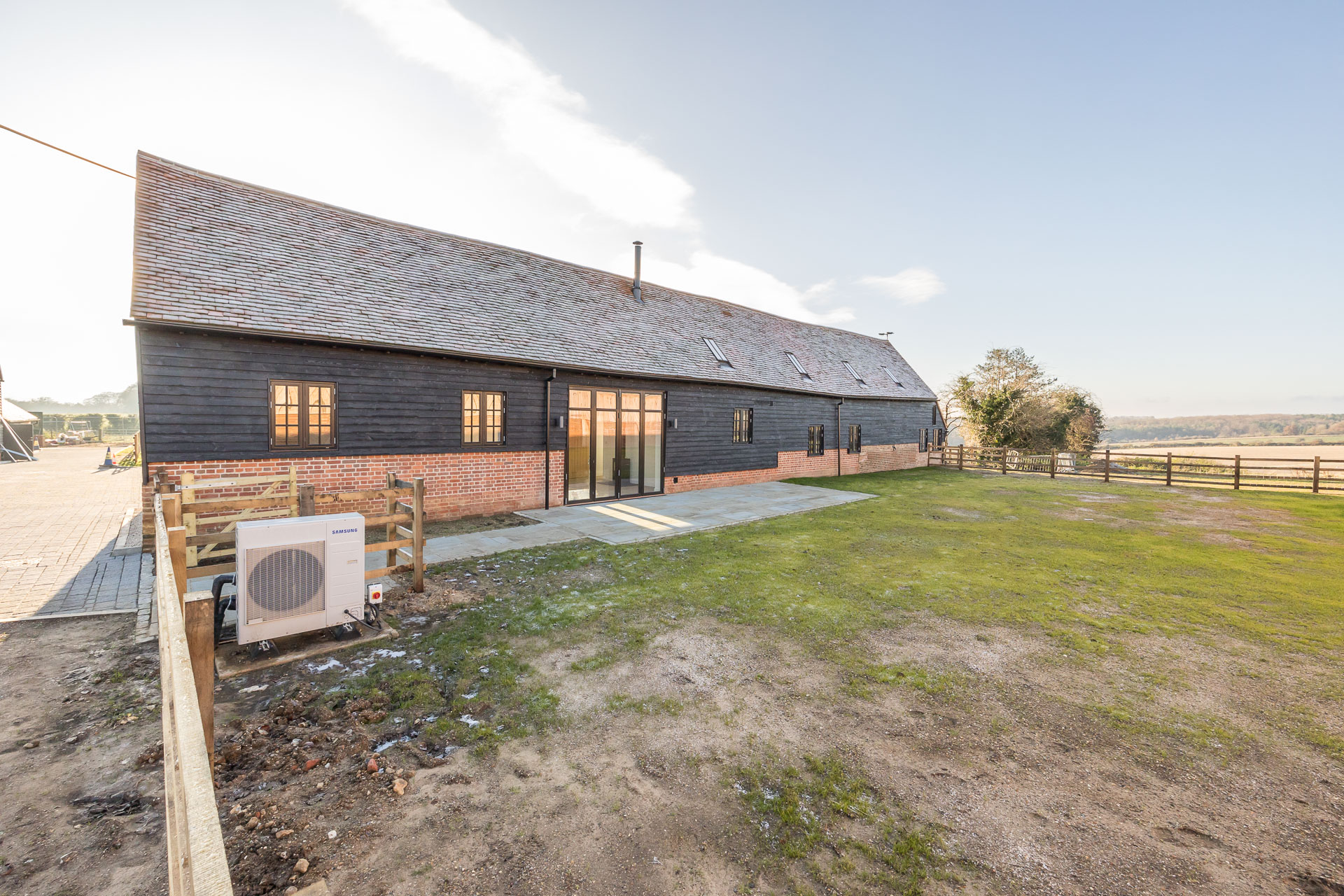 Rear external view from the garden of a refurbished barn with rural land in the background at Hard to Find Farm.